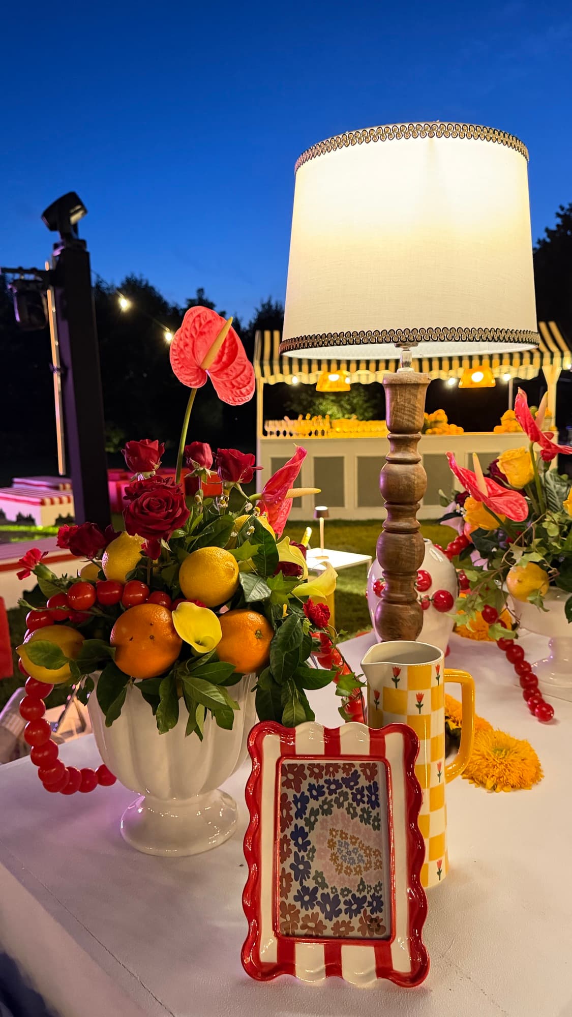Centrotavola con agrumi, rose e anthurium accanto alla lampada da tavolo